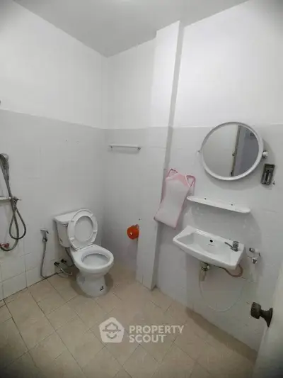 Compact bathroom with white tiles and basic fixtures, ideal for minimalist living.