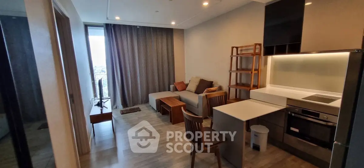 Modern living room with open kitchen, cozy seating, and large window view.