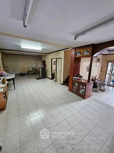 Spacious open-plan living area with tiled flooring and ample natural light, perfect for versatile home setups.