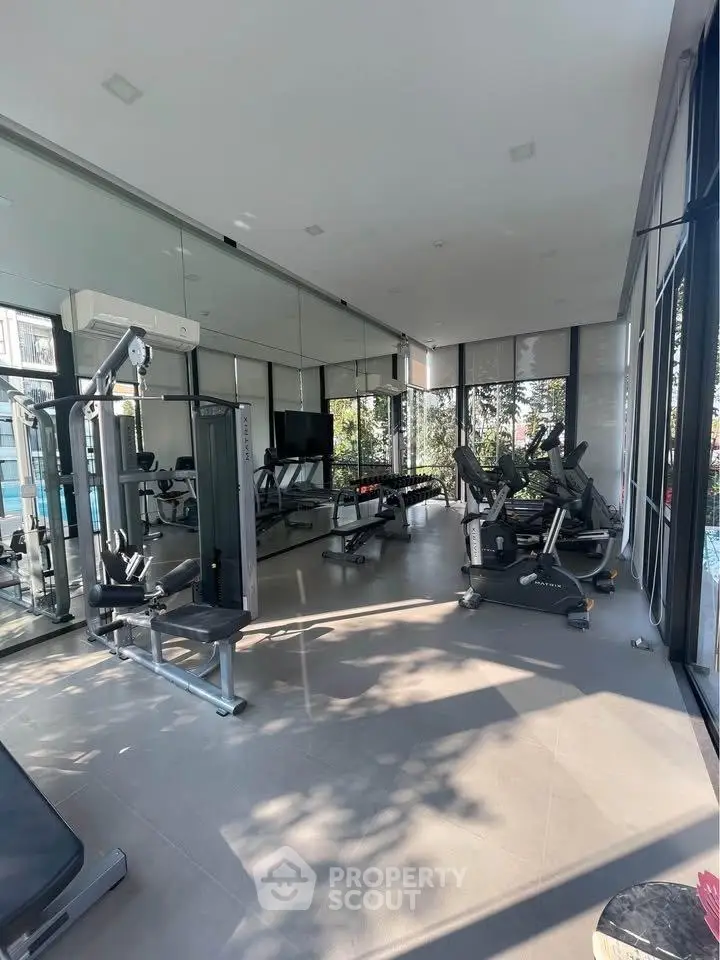 Modern gym with state-of-the-art equipment and floor-to-ceiling windows offering a scenic view.
