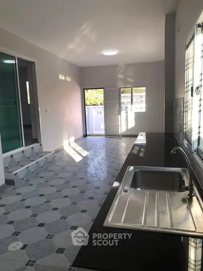 Spacious kitchen with sleek countertops and ample natural light, perfect for modern living.