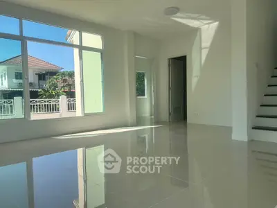Spacious sunlit living room with glossy tiled floors and large windows in modern home.