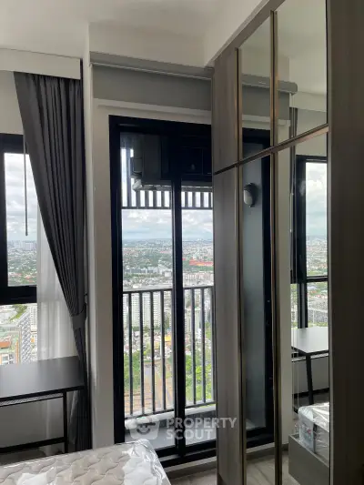 Modern bedroom with balcony and stunning city view, featuring sleek furniture and large windows.