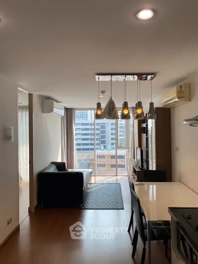 Modern living room with city view, stylish lighting, and sleek furniture in a high-rise apartment.