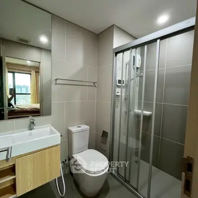 Modern bathroom with sleek design, featuring glass shower and city view window.