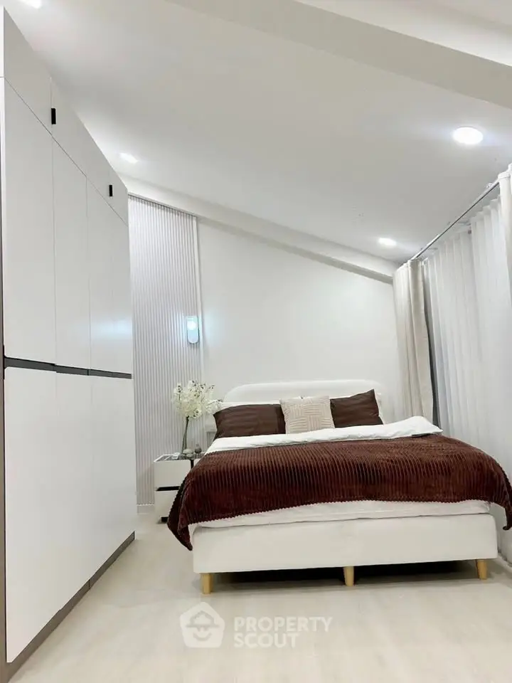 Modern bedroom with sleek white wardrobe and cozy bed, perfect for relaxation.