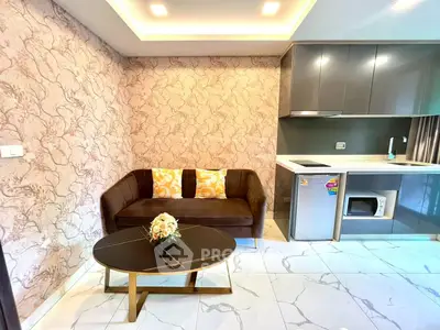 Modern living room with stylish sofa and compact kitchen in open layout apartment.