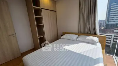 Modern bedroom with large window and city view, featuring a cozy bed and wooden wardrobe.