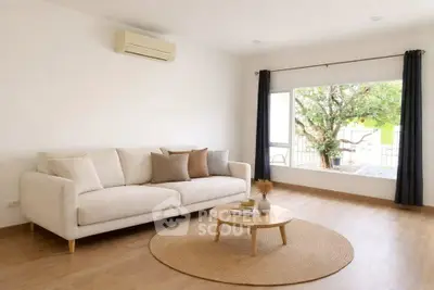 Spacious living room with cozy sofa and large window overlooking garden