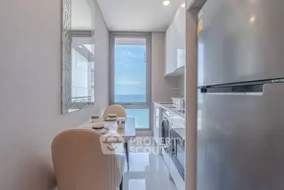 Modern kitchen with ocean view, featuring sleek appliances and elegant dining setup.
