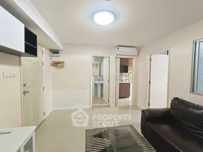 Spacious living room with modern decor and natural light, featuring a cozy leather sofa and stylish glass coffee table.