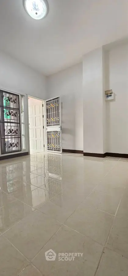 Spacious room with glossy tiled floor and secure door, ideal for modern living.