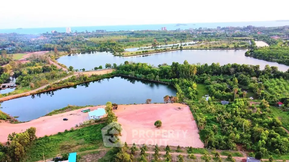 Stunning aerial view of expansive land with lush greenery and serene water bodies, perfect for development.