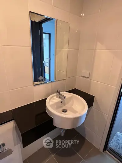Modern bathroom with sleek white sink and black countertop in stylish apartment.