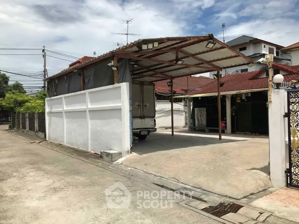 Spacious residential carport with covered parking and adjacent house in suburban neighborhood.