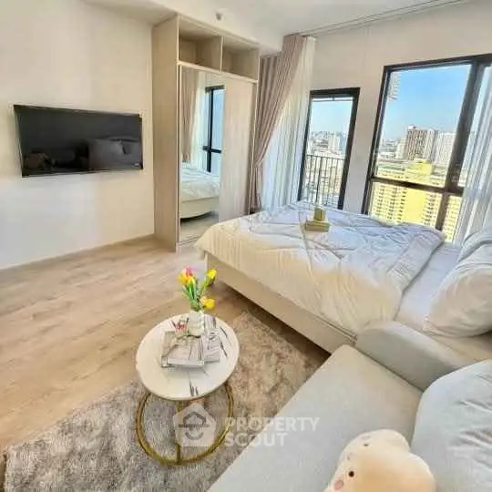 Modern bedroom with city view, cozy seating area, and stylish decor in a high-rise apartment.