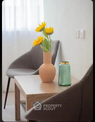 Stylish modern living room with elegant chairs and decorative vases on a wooden table.