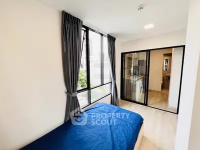 Modern bedroom with large window and washing machine in sleek apartment