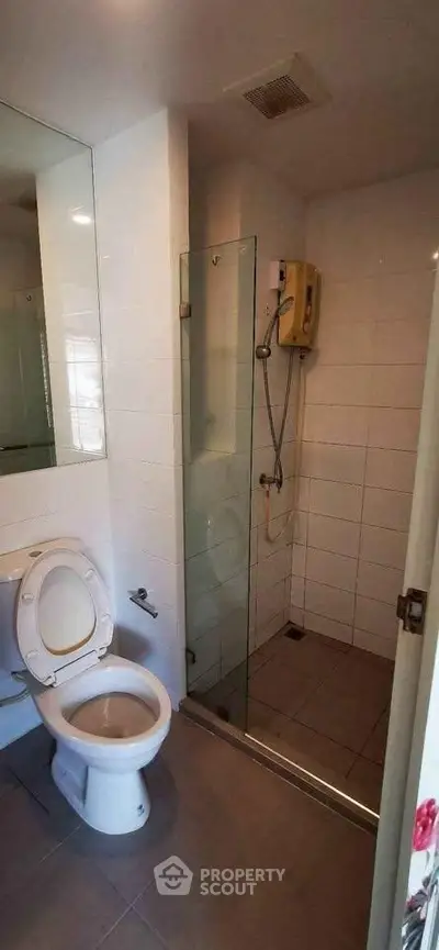 Modern bathroom with glass shower and white fixtures in a sleek apartment.