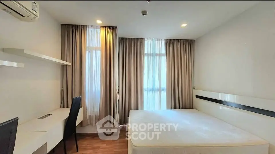 Modern bedroom with natural light, minimalist design, and workspace area.