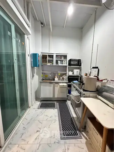 Compact kitchen with modern appliances and sliding glass doors, ideal for efficient cooking and storage.