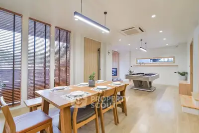 Spacious modern dining room with elegant wooden table and pool table, perfect for entertaining.