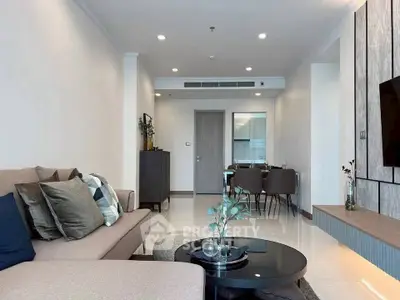 Modern living room with stylish decor and open dining area, featuring neutral tones and contemporary furniture.