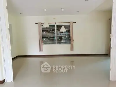 Spacious empty living room with large window and modern lighting fixtures.