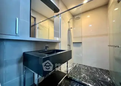 Modern bathroom with sleek black sink and glass shower enclosure