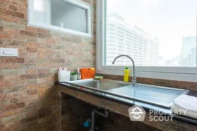 Modern kitchen with city view, featuring sleek sink and brick backsplash.