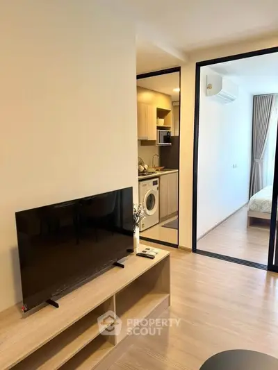 Modern apartment interior with open layout, featuring a cozy living room and a glimpse of the bedroom.
