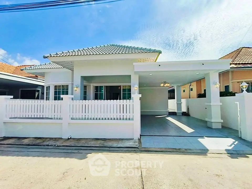 Charming single-story house with spacious carport and white picket fence under a clear blue sky.