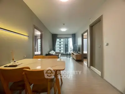 Modern apartment interior with open living and dining area, featuring sleek furniture and natural light.