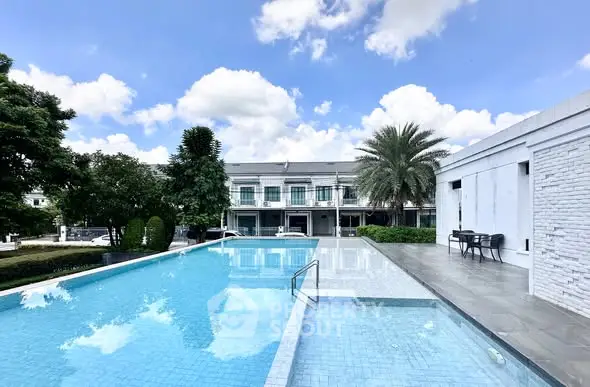 Luxurious outdoor pool with modern architecture and lush greenery under a clear blue sky.