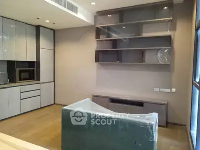 Modern living room with sleek kitchen and built-in shelves, featuring a wrapped sofa.