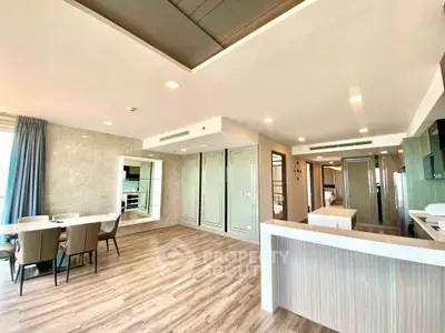 Spacious modern living room with open kitchen and elegant dining area, featuring stylish decor and ample natural light.