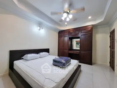 Spacious bedroom with elegant wooden wardrobe and ceiling fan, perfect for comfort and style.