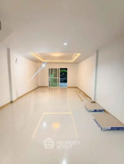 Spacious unfurnished room with glossy tiled flooring and recessed lighting, ideal for customization.