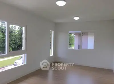 Bright empty room with large windows and wooden flooring, ideal for customization.