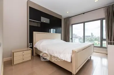 Modern bedroom with large window and city view, featuring elegant decor and natural light.
