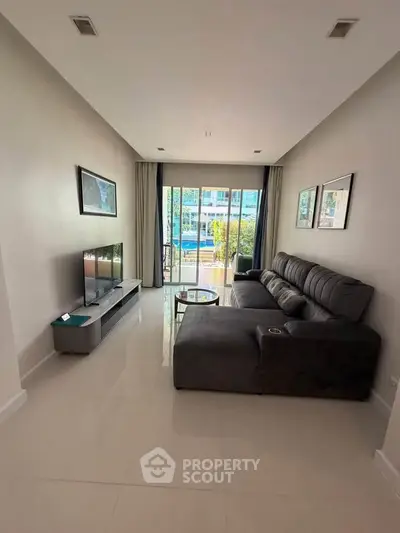 Spacious living room with modern sofa and large windows offering a bright view.