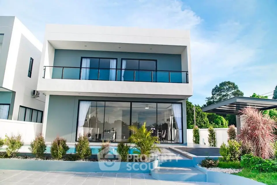 Modern two-story house with large windows and landscaped garden