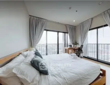 Spacious bedroom with large windows and balcony offering stunning city views.