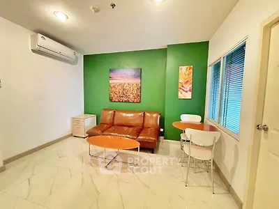 Modern living room with green accent wall, leather sofa, and air conditioning