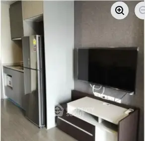 Modern kitchen with sleek appliances and wall-mounted TV in compact living space.