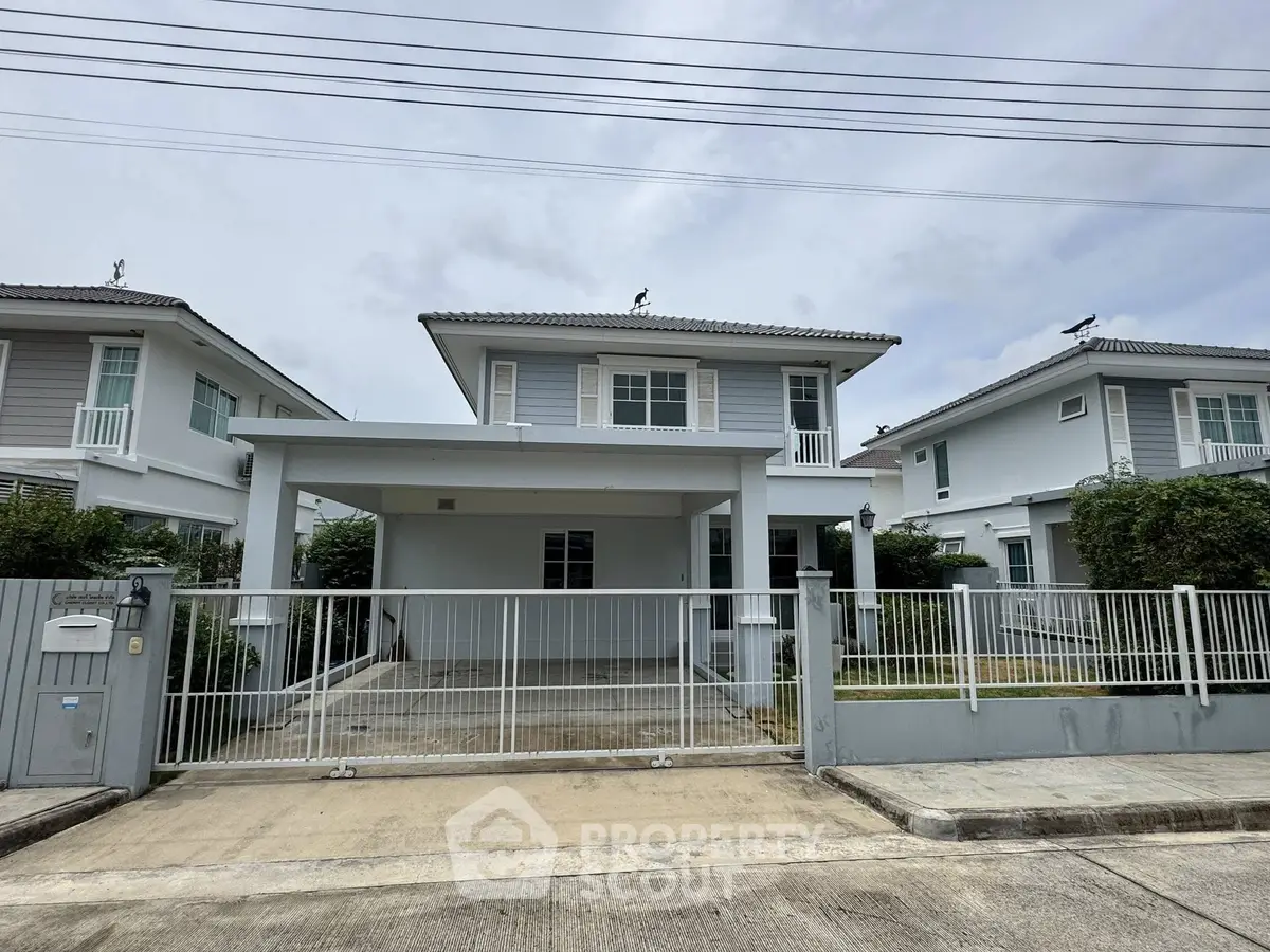Modern two-story house with gated driveway and manicured garden in a serene neighborhood.