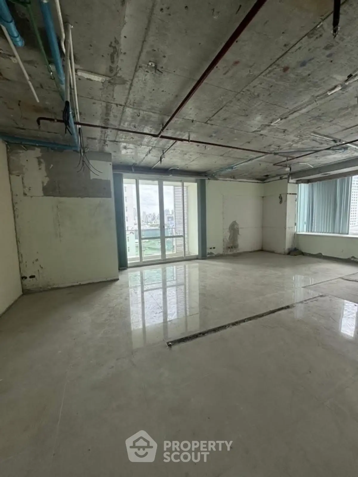 Spacious unfinished apartment with large windows and city view, ideal for customization.