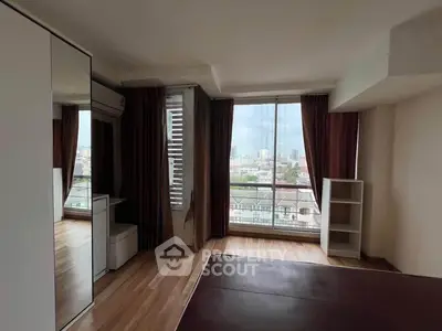 Spacious bedroom with large window offering stunning city views, featuring modern decor and ample natural light.