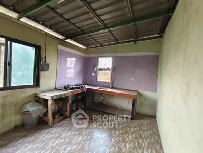Spacious kitchen with tiled floor and ample natural light, featuring a large window and basic countertops.