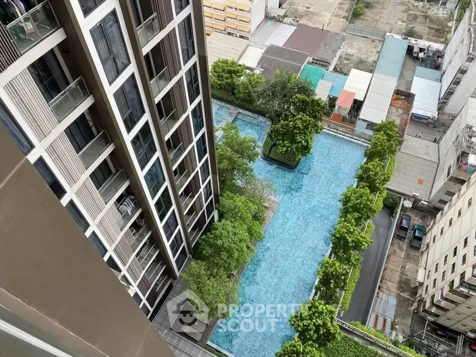 Stunning aerial view of modern high-rise building with luxurious swimming pool and lush greenery.